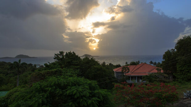 A peaceful view of Grenada with lush greenery and a sunset over the sea