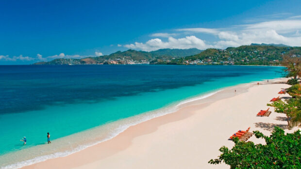 Turquoise water and sandy shore at Grenada coastline with people enjoying the beach
