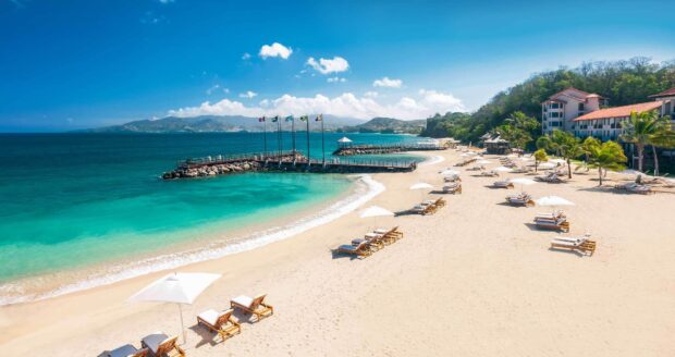 A scenic view of a tropical beach in Grenada with clear turquoise water and sandy shore