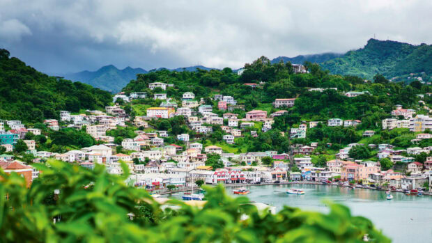 A vibrant Grenada town with colorful houses nestled among green hills and a calm bay