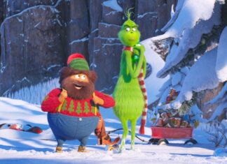 The Grinch and his companion standing in a snowy forest with Christmas decorations