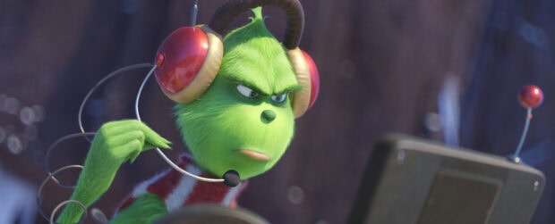 The Grinch wearing red headphones and looking focused on a device