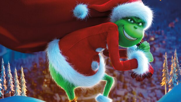 The Grinch wearing a Santa suit with a mischievous smile on a snowy hill
