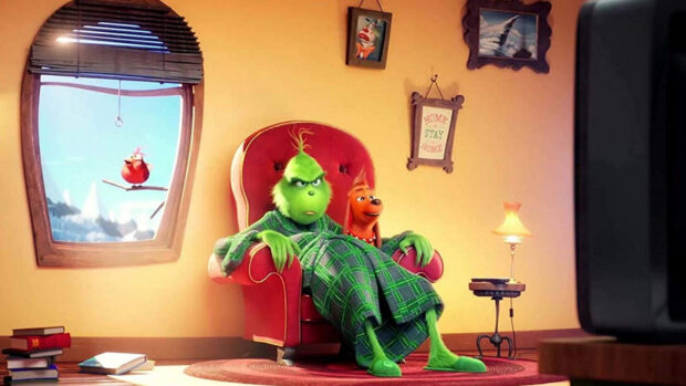The Grinch relaxing in a red armchair with his dog in a cozy living room