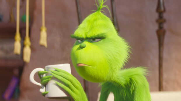 The Grinch character holding a white cup with a displeased expression on his face