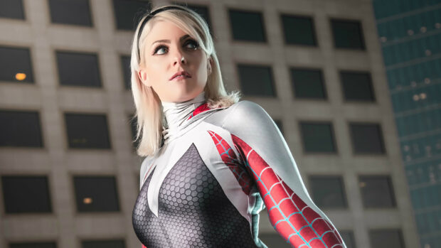 Gwen Stacy stands confidently in her distinctive suit against a modern building background