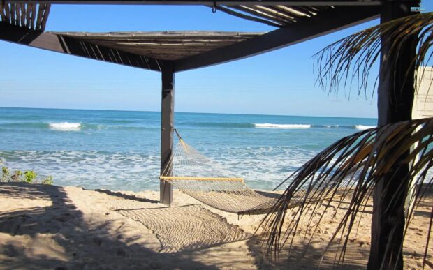 A peaceful hammock on the sand under a wooden shelter by the ocean in Haiti