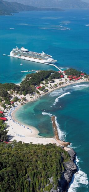 Aerial view of Haiti coastline with cruise ship docked near tropical beach and lush greenery