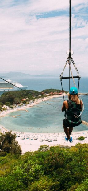 A zipline rider enjoying a scenic view of the coast and clear blue water in Haiti