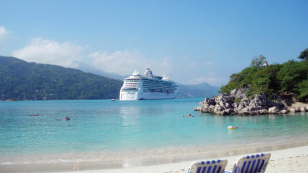 A cruise ship near a tropical island with clear turquoise water in Haiti