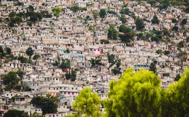 Dense urban houses in Haiti hillside with vibrant trees in foreground