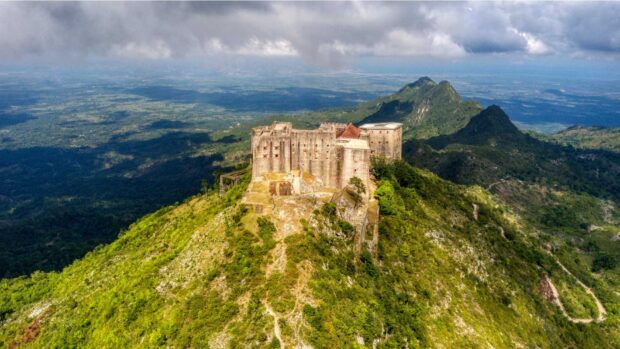 A historic Haiti castle sits atop a green mountain surrounded by vast natural landscape