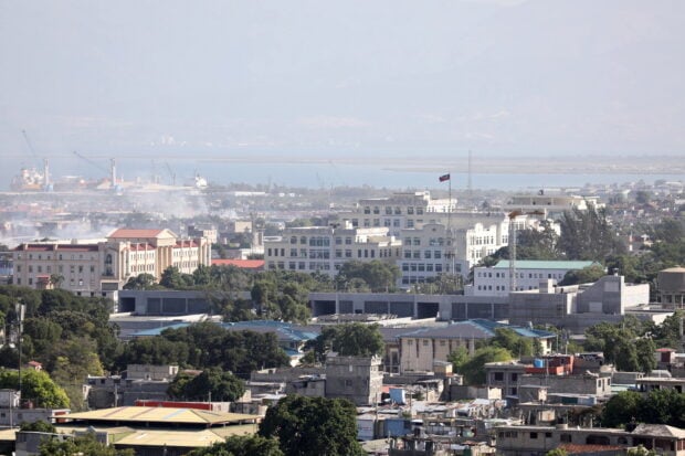 A panoramic view of Haiti cityscape with buildings trees and a flag on a clear day