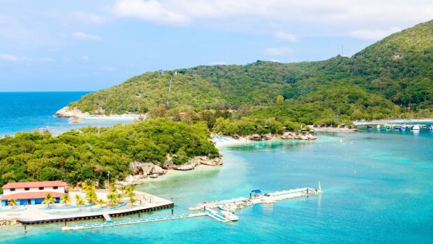 A beautiful Haiti coastline with lush greenery and clear turquoise water surrounded by hills