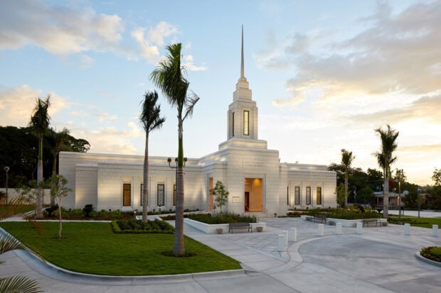 A white temple surrounded by palm trees and greenery in Haiti during sunset