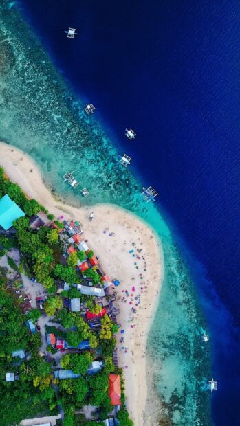 A vibrant aerial view of Haiti coastline with turquoise water and colorful beach umbrellas