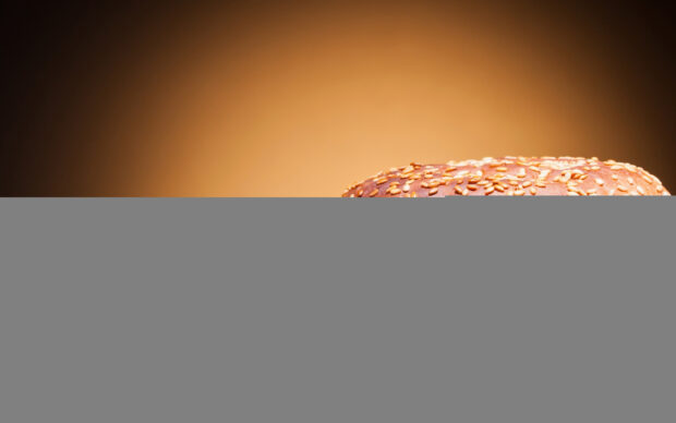 Fresh hamburger bun with sesame seeds on a brown gradient background