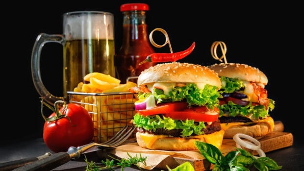 A delicious hamburger with fresh lettuce tomato and cheese served with fries and beer