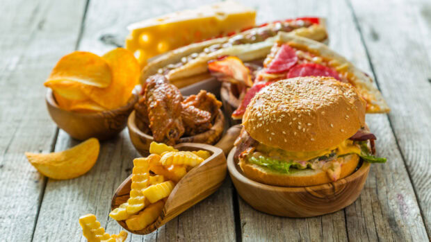 A delicious hamburger with fries wings and chips on wooden table
