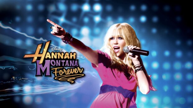 A blonde woman wearing a pink dress singing and pointing on stage with Hannah Montana logo in the background