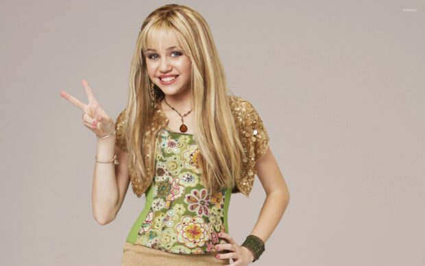 Hannah Montana showing a peace sign wearing a floral top and gold jacket