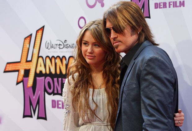 Hannah Montana standing with a man at a premiere event
