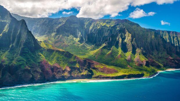 Lush green cliffs and turquoise ocean along the Hawaiian coastline