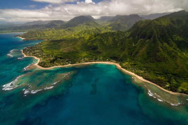 Aerial view of lush Hawaiian Islands with coastline and ocean under cloudy sky