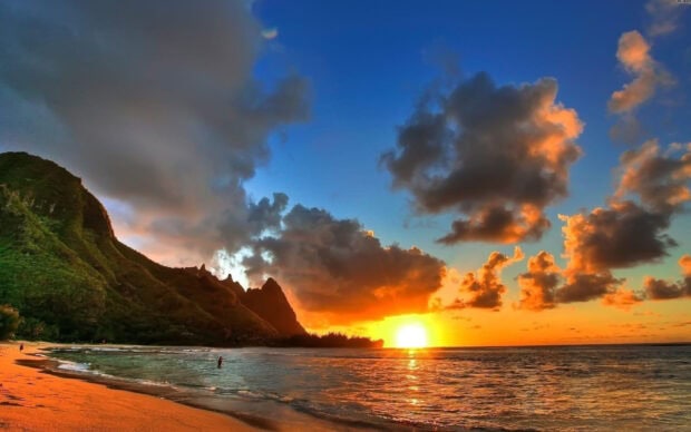 Sunset over the Hawaiian Islands with lush green cliffs and vibrant sky