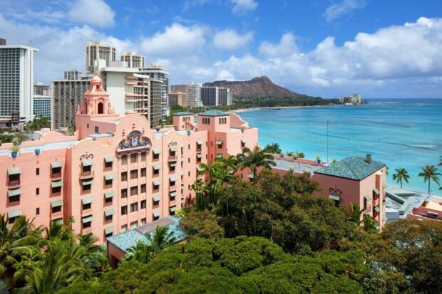 Historic architecture near Hawaiian ocean with lush greenery and mountain in background