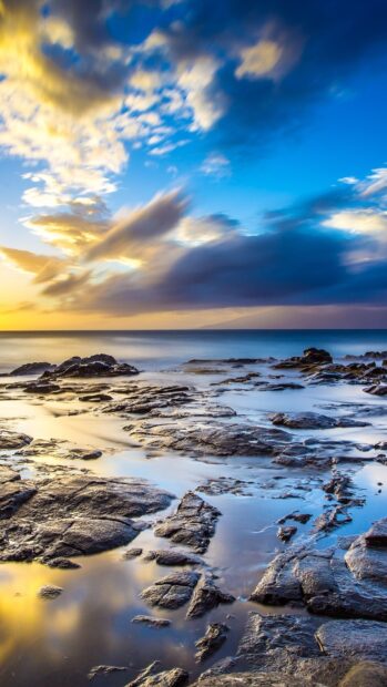 Rocky shore under the Hawaiian ocean during a colorful sunset with vibrant clouds