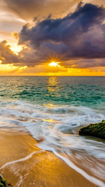 Golden sunrise over Hawaiian ocean waves and sandy beach at sunset