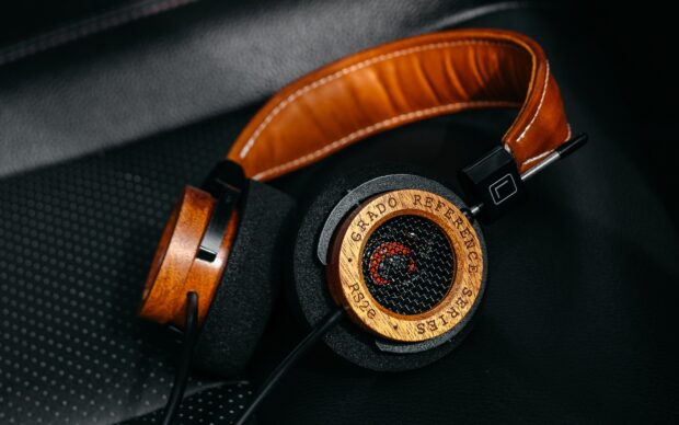 Vintage wooden headphones with foam ear pads lying on black textured surface