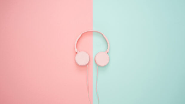 Pink headphones placed on split pink and blue background with clear lighting