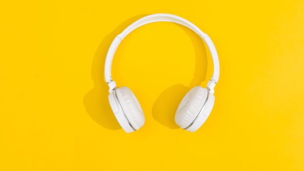 White headphones placed on a bright yellow surface showing headphones clearly