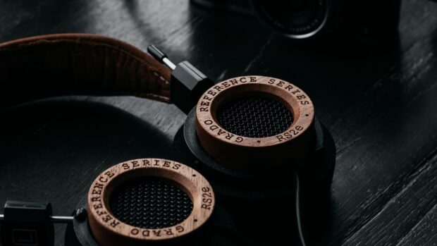Wooden headphones from reference series placed on a dark surface with a black cable attached