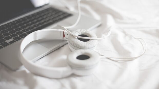 White headphones resting on a laptop keyboard on a white surface