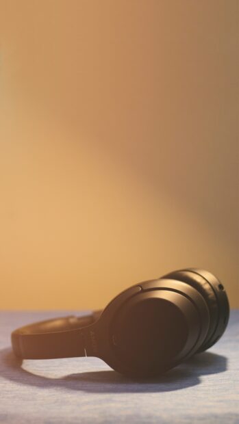 Close up of headphones placed on surface with warm lighting and soft background