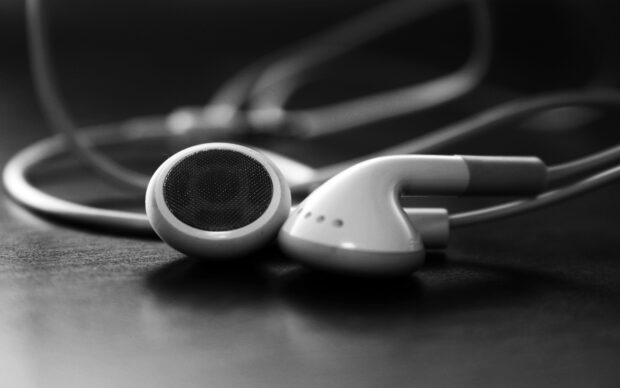 Close up of earphone headphones resting on a dark surface with a tangled wire