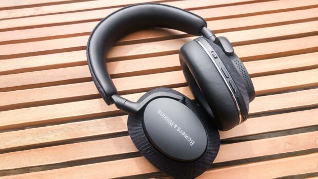Black Bowers and Wilkins headphones resting on wooden surface with padded ear cups