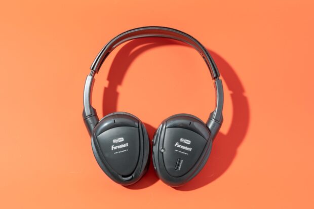 Black Farenheit headphones resting on an orange surface with wireless technology symbol