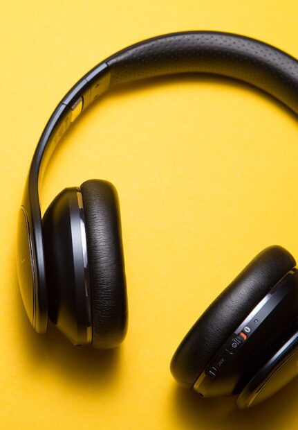 Black headphones resting on a yellow surface showing audio controls and padding