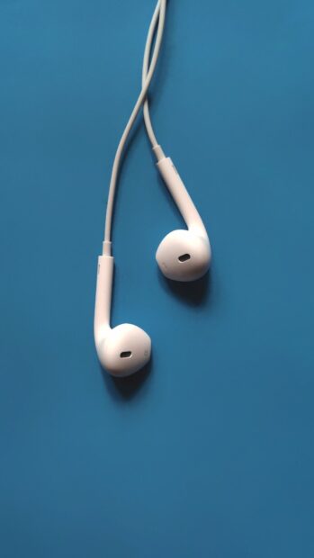 White headphones placed on blue surface with visible wires