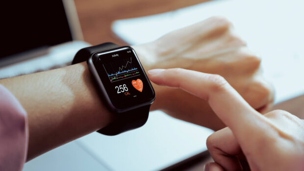 Person checking health data on smartwatch display with activity and heart rate graphs