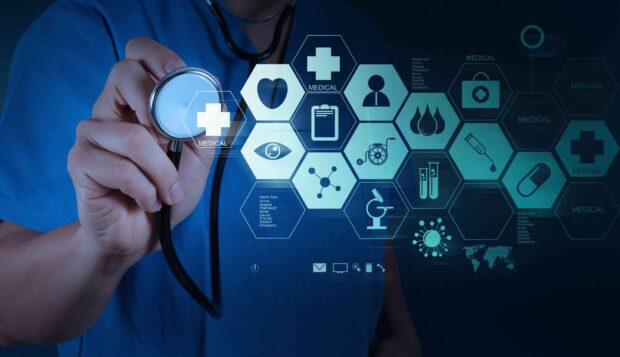 A medical professional is holding a stethoscope with health care icons displayed digitally
