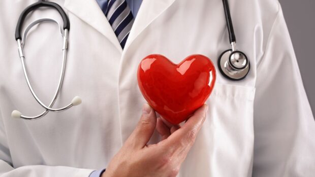 Doctor holding a red heart symbol representing health care and heart care concepts