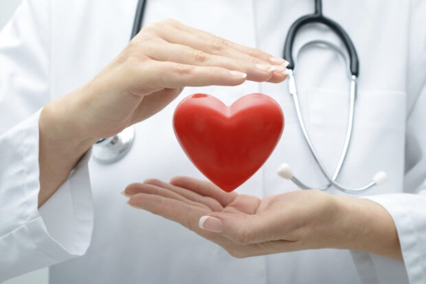 A doctor protecting a red heart symbol representing health and care