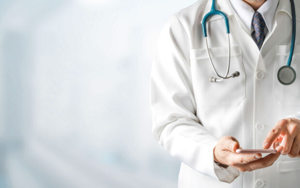 Doctor with stethoscope using smartphone for health consultation