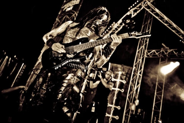A heavy metal guitarist playing intense music on stage during a live concert performance