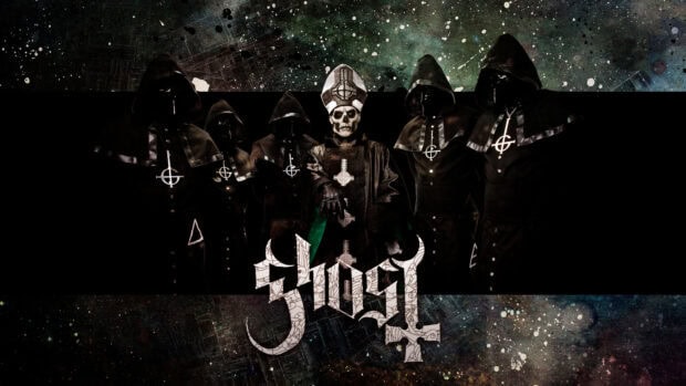 The heavy metal band Ghost members dressed in dark robes with a skull faced lead singer